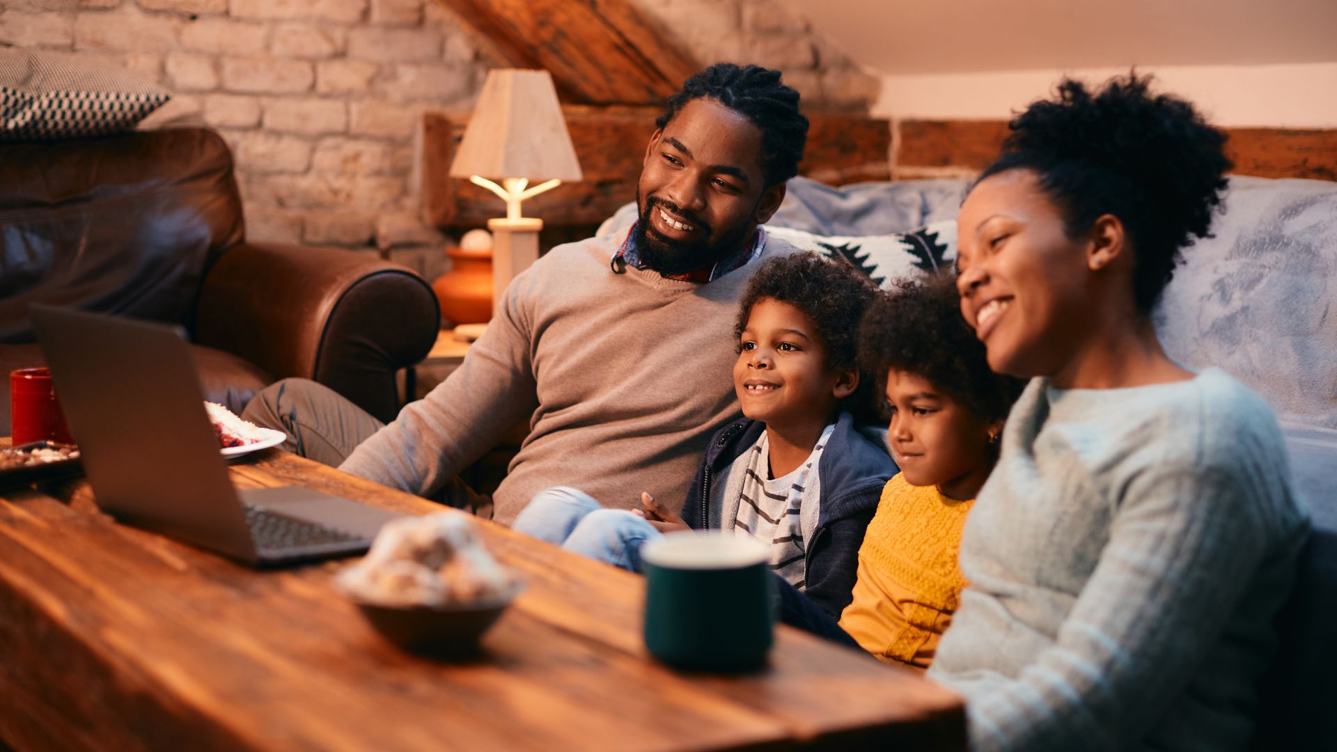 Family Online A Black family smiles while watching a laptop together, representing Growth Groups at a church in Kingston, NY.
